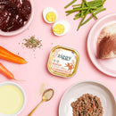 Boîte de pâtée pour chat boeuf et poulet en situation avec les ingrédients bruts à côté