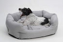 Chien blanc et noir dans un panier pour chien gris