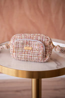 Pochette distributeur de sacs d'hygiène pour chien en tweed rose chiné sur une table marbre et or