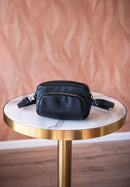 Pochette noire rendu cuir sur une table marbre et or