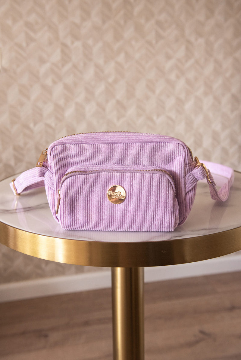 Pochette distributeur de sac à crotte lila sur une table marbre et or