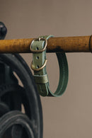 Collier pour chien en cuir vert accroché sur une barre en bois